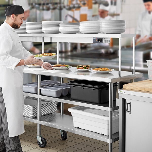 A chef in a white uniform preparing food on a Regency expeditor table with undershelves.
