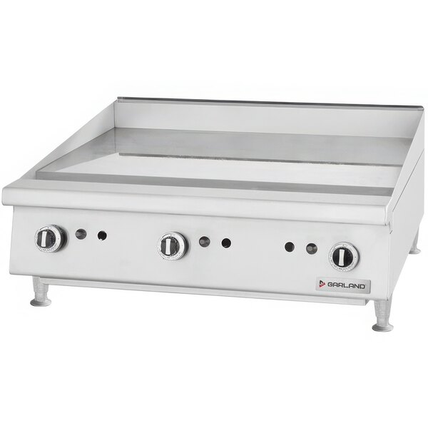 A white rectangular countertop griddle with a chrome top and manual controls.