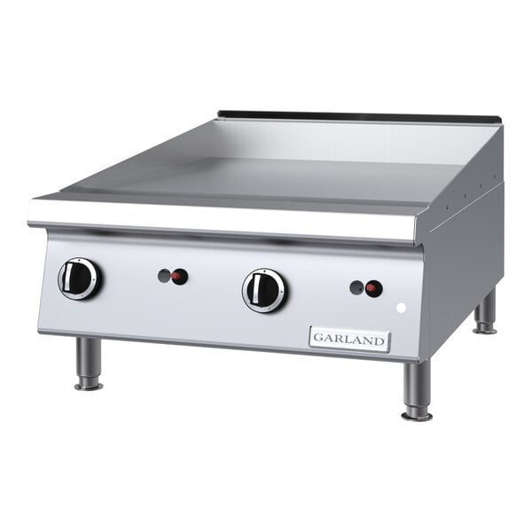 A stainless steel 24-inch natural gas countertop griddle with manual controls and chrome plating.