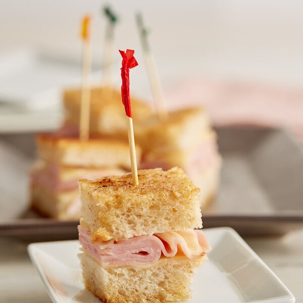 A small ham and cheese sandwich with a Royal Paper bamboo frilled club toothpick.