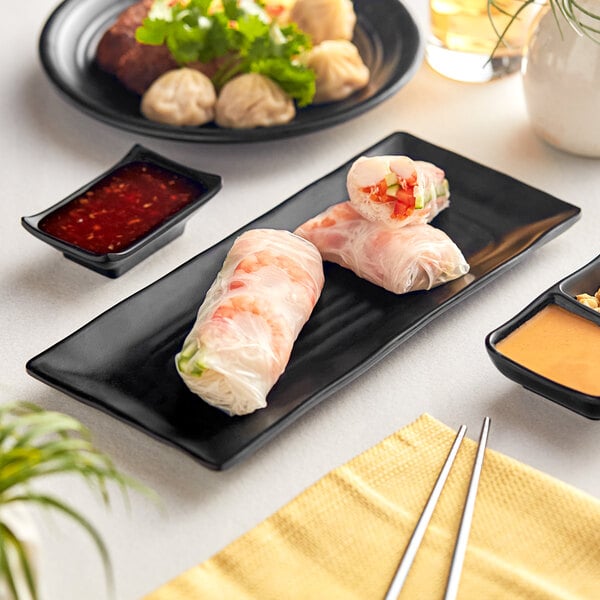 A black Acopa Izumi melamine platter with food on a table.