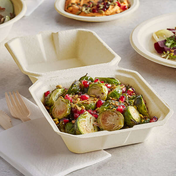 A Tellus Products bagasse clamshell container filled with food on a plate.