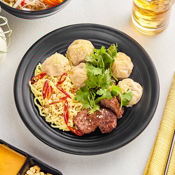 A plate of food with noodles, meat, and vegetables on an Acopa Izumi matte black melamine plate.