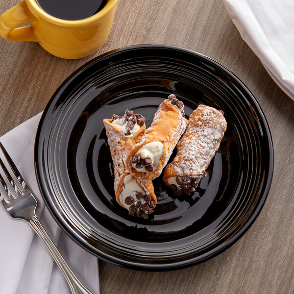 A Tuxton Concentrix black china plate with two pastries and a cup of coffee.