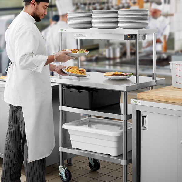 A man in a white chef's uniform working on a Regency expeditor table.