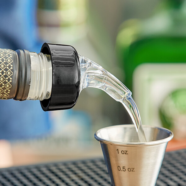 A person using a Franmara clear liquor pourer to pour a shot of liquor into a measuring cup.