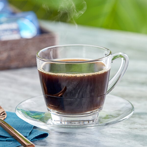 A glass cup of Lavazza decaf coffee on a saucer.