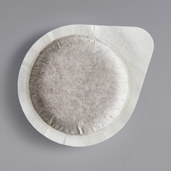 A round white box of Lavazza Dek decaf single serve espresso pods with brown spots.