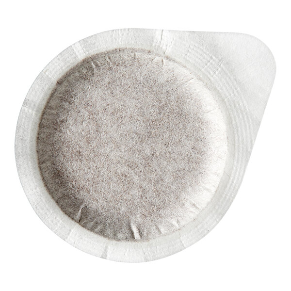 A round, white, single-serve coffee pod with a textured, filter-like surface and a small tab on one side.