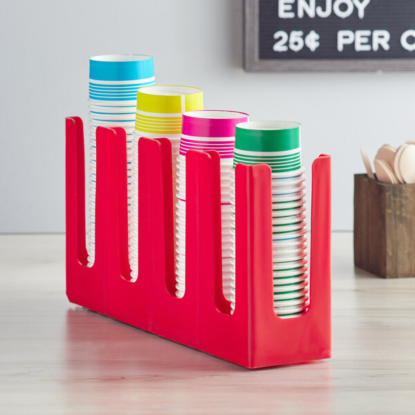 A red Choice countertop cup and lid organizer with cups in it.