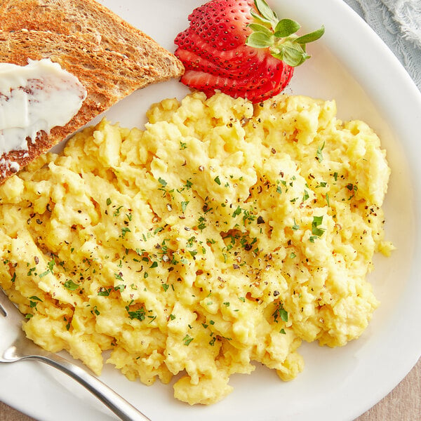 A plate of JUST Egg scrambled eggs with strawberries.