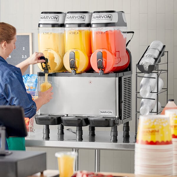 A close-up of a plastic container of yellow liquid with a red and white label for Carnival King Peach Slushy Concentrate.