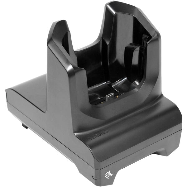 A black Zebra single slot charger and communication cradle for TC21 and TC26 handheld computers on a table.