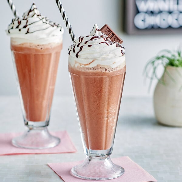 A close-up of two glasses of Hershey's chocolate milkshake with straws.