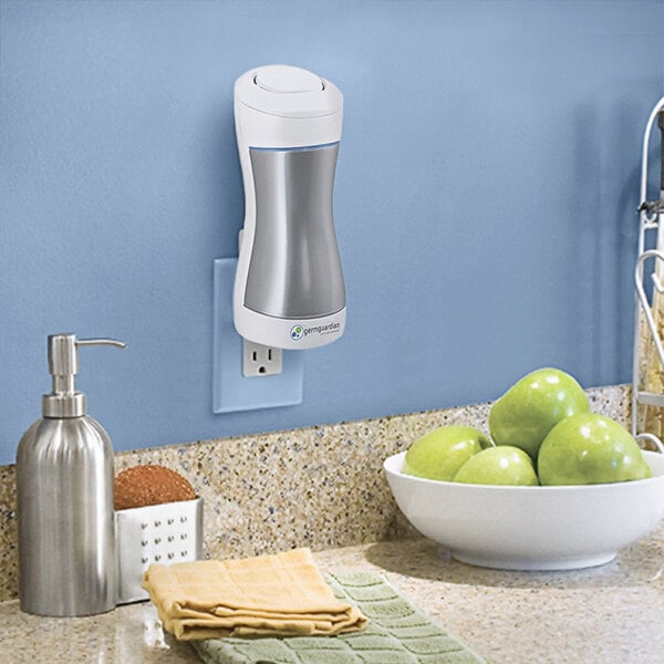 A Guardian Technologies Germ Guardian plug-in air sanitizer on a kitchen counter next to a bowl of green apples.