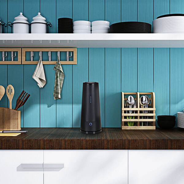 A Guardian Technologies Germ Guardian air sanitizer on a kitchen counter with white cabinets and shelves.