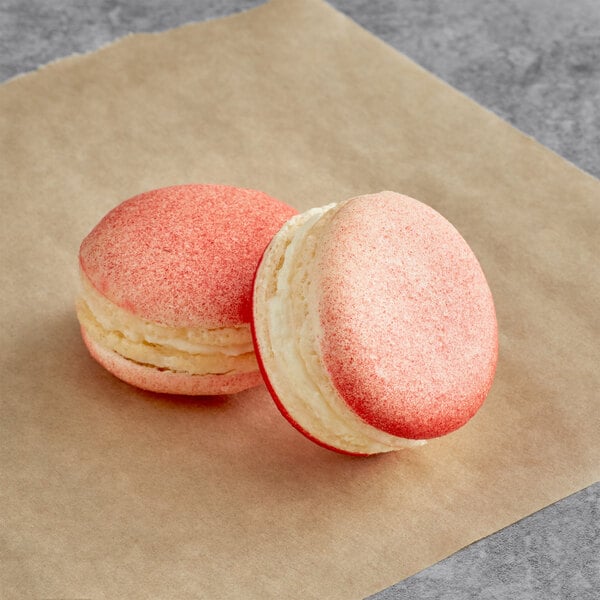 Two pink and white Lychee Macarons on a piece of paper.