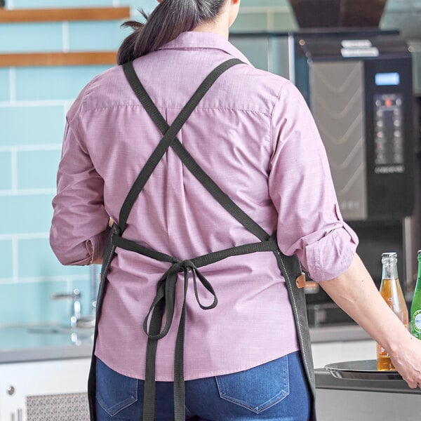 A woman wearing a black Acopa Hazleton cross-back apron.