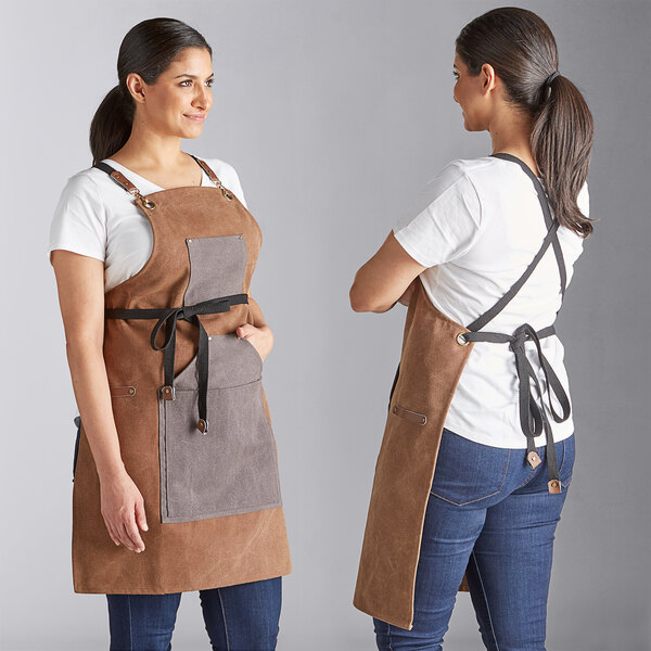 Two women wearing brown and blue Backyard Pro grilling aprons.