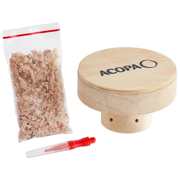 A wooden drum with a bag of wood shavings next to a plastic bag of wood chips and a red cap.