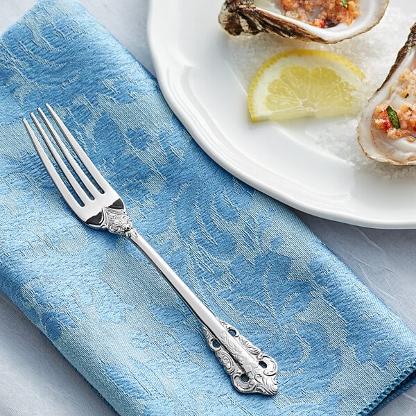 A plate of oysters with a fork and a slice of lemon.