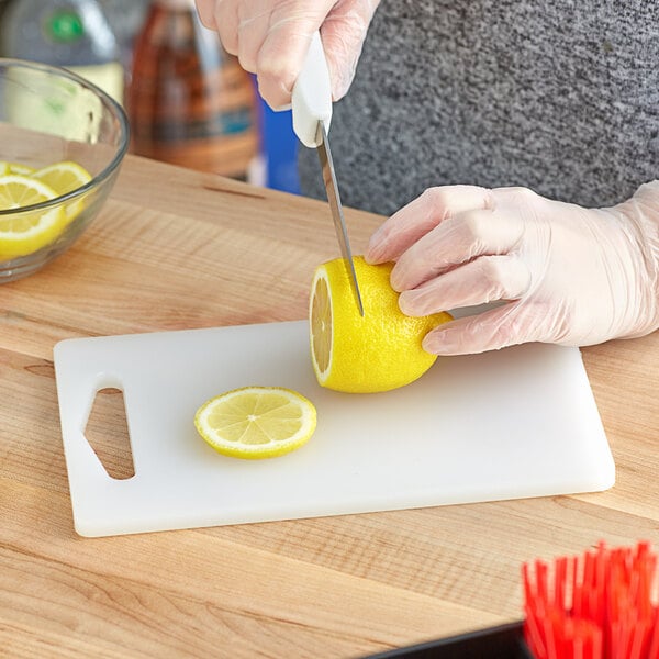 Someone chopping a lemon on a white cutting board