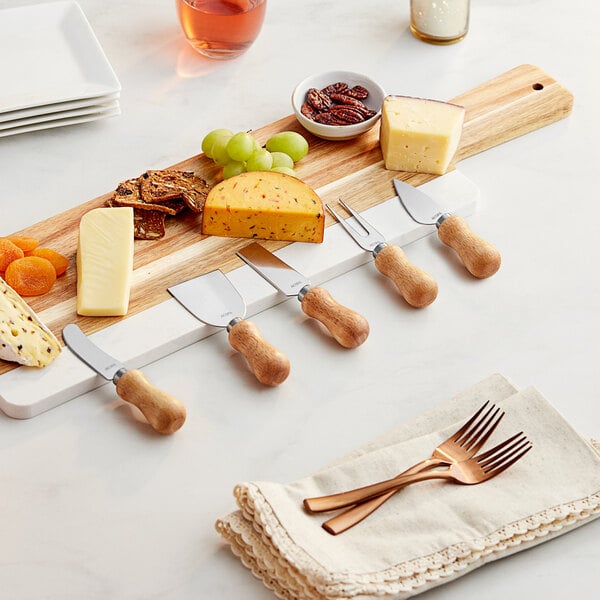 Multiple cheese knives beside cheeses on a cutting board