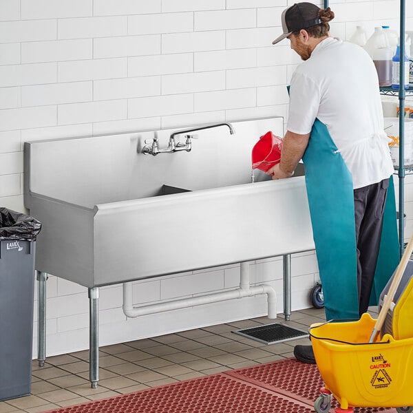 A man cleaning a Regency stainless steel utility sink.