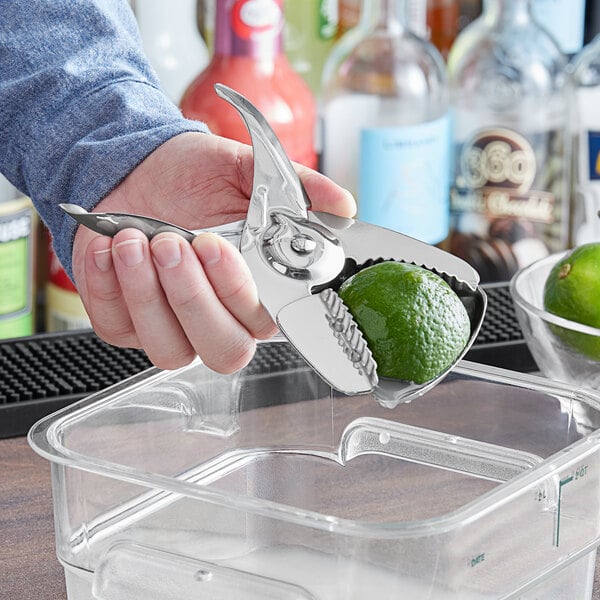 Bartender juicing a lime with a stainless steel citrus squeezer