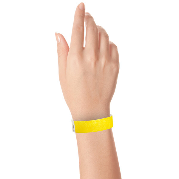 A close-up of a hand wearing a yellow Carnival King wristband.