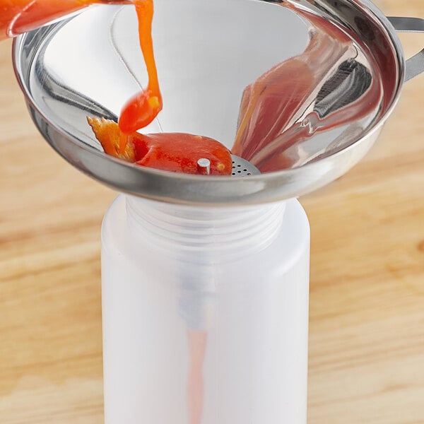 A person using a Choice strainer to pour liquid into a container over a funnel.