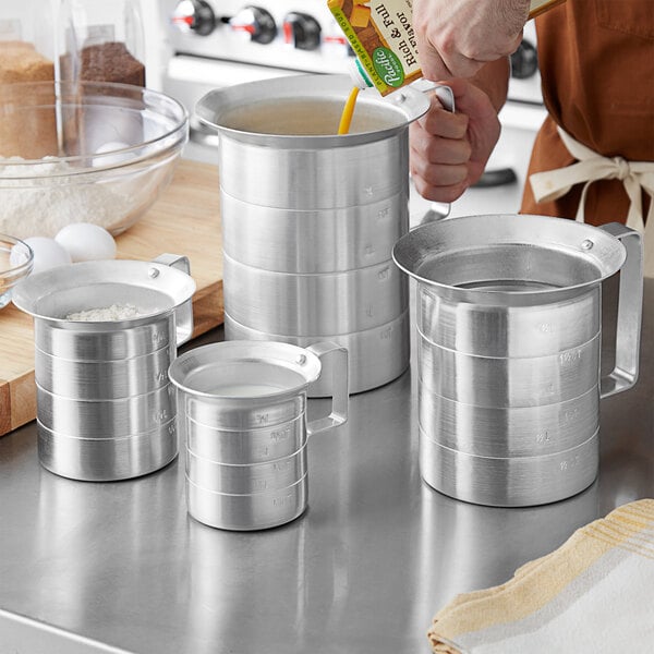 A person using the Choice aluminum measuring cups with pour lips to measure liquid.