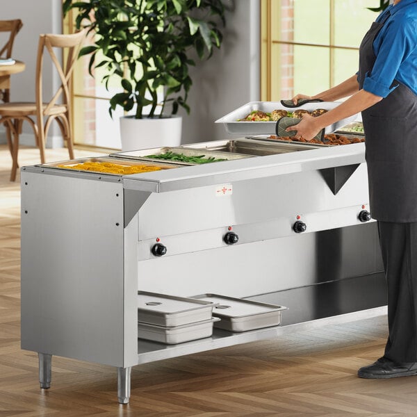 A stainless steel six-pan electric hot food table with a partially enclosed base, used for serving hot food in a commercial setting.