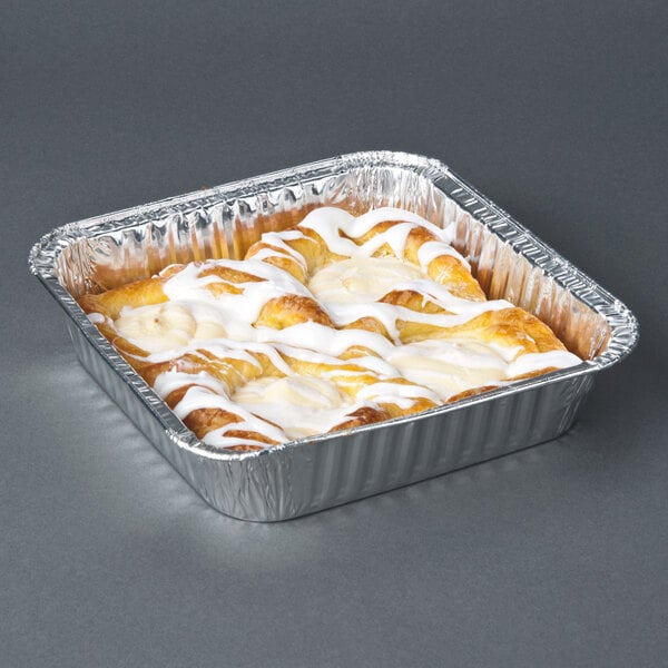 An 8" square foil cake pan with a white frosted cake inside.