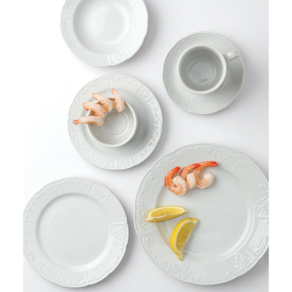 A group of Tuxton Chicago bright white plates with shrimp and lemon.