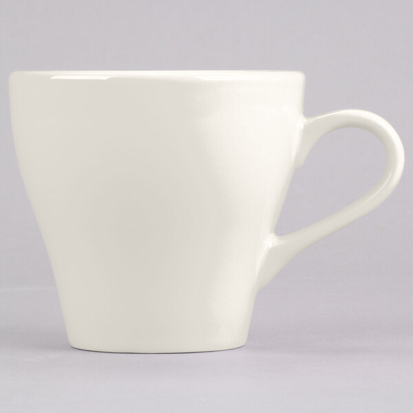 A close-up of a white Tuxton Europa cappuccino mug with a handle.