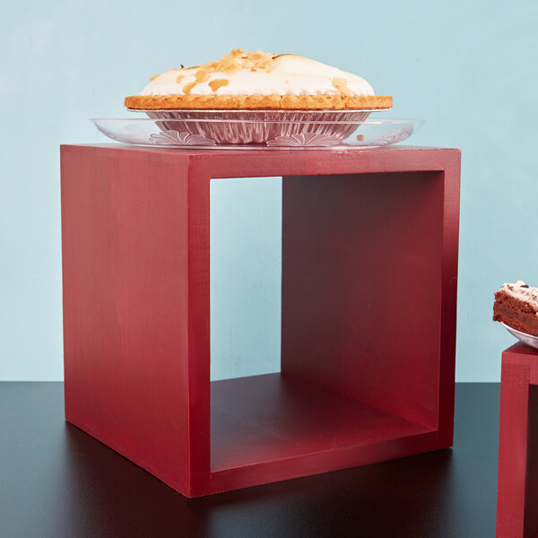 A pie on a plate on a mahogany wood riser.