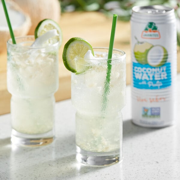 A couple of Jarritos Coconut Water with Pulp on a table with lime slices.