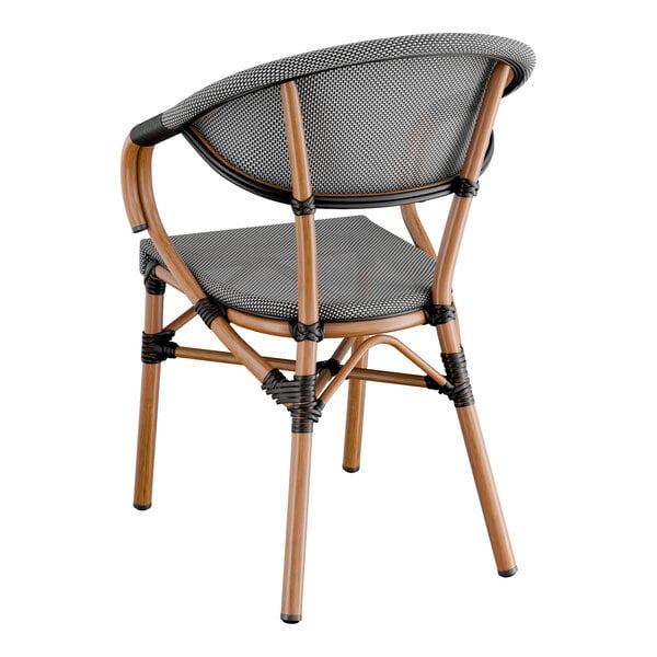 A Lancaster Table & Seating black and white outdoor arm chair with a wicker back and wooden frame.