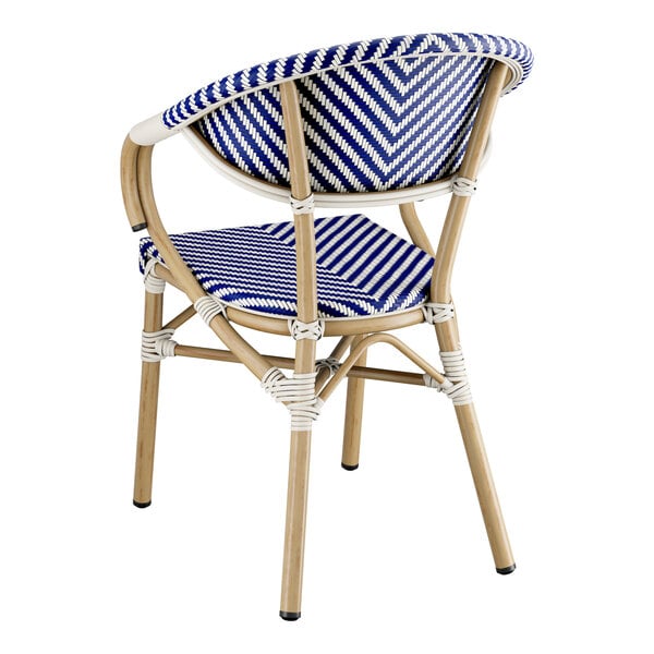 A Lancaster Table & Seating blue and white striped outdoor arm chair with a wooden frame.