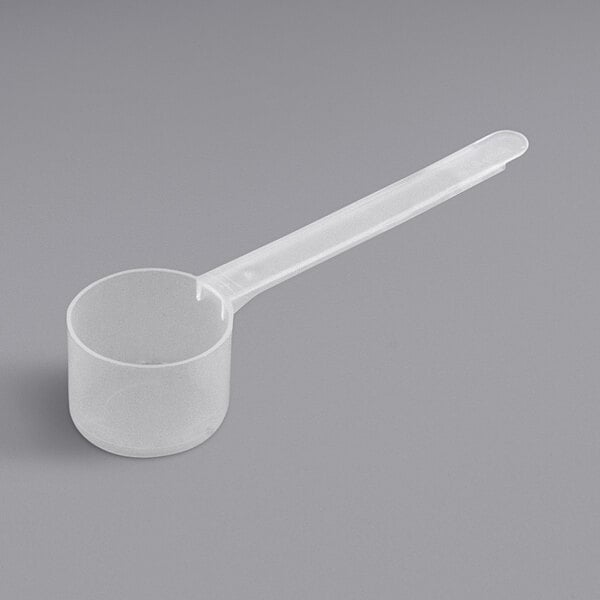 A clear plastic measuring spoon with a long handle.