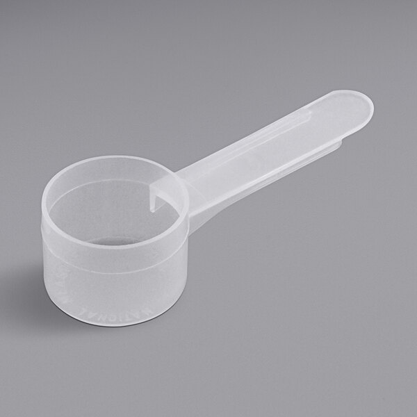 A clear plastic container with a white plastic measuring spoon with a medium handle.