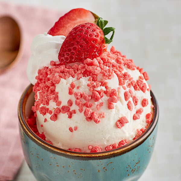 A bowl of Dutch Treat Strawberry Krunch topping on ice cream with strawberries and whipped cream.