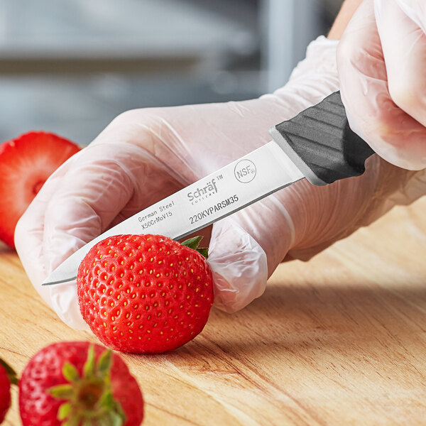 Chef using a paring knife to slice through a strawberry