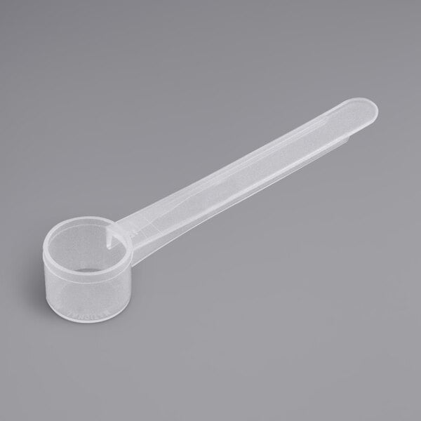 a plastic measuring spoon on a gray background
