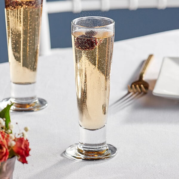 Two Libbey Catalina champagne flutes with fruit on a table.