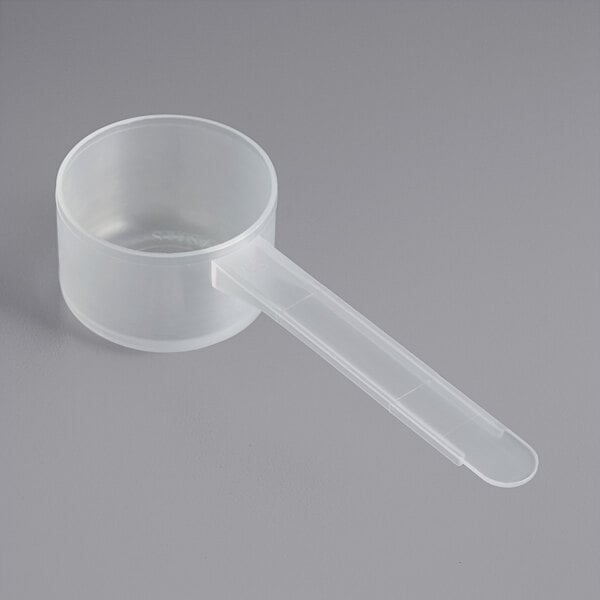 A clear plastic measuring scoop with a long handle.