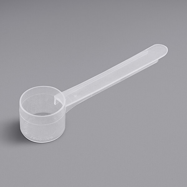 a plastic measuring spoon on a gray background