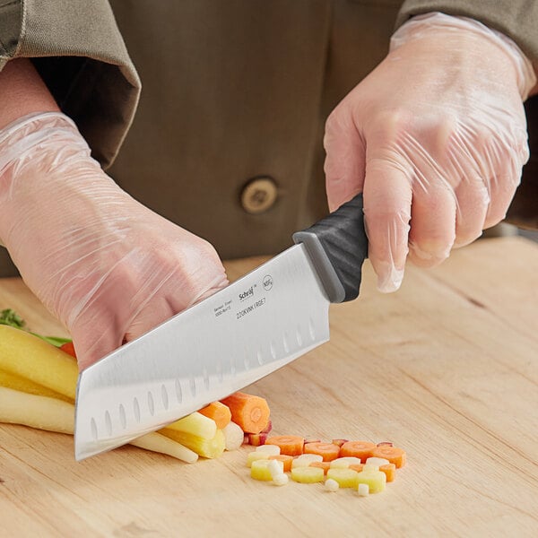 Chef using a nakiri knife to chop carrots