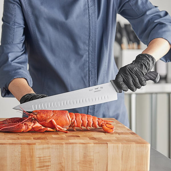 A person using a Schraf chef knife to cut a lobster.